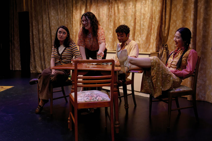 Four friends sit around a table having a drink.