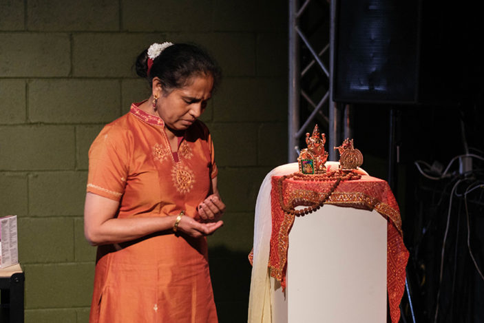 A woman prays to an alter in her home.