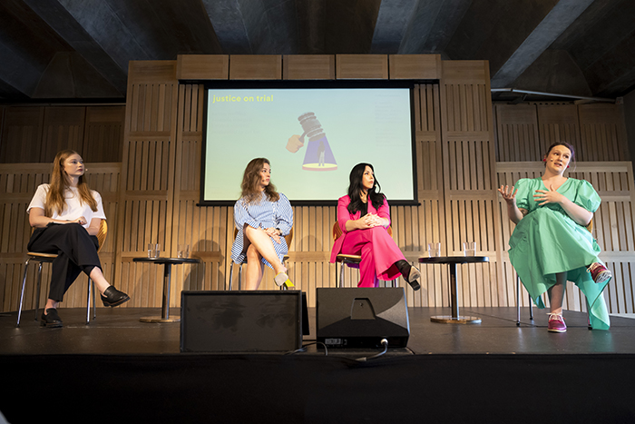 Four women sit on stage in front of a screen having a conversation.