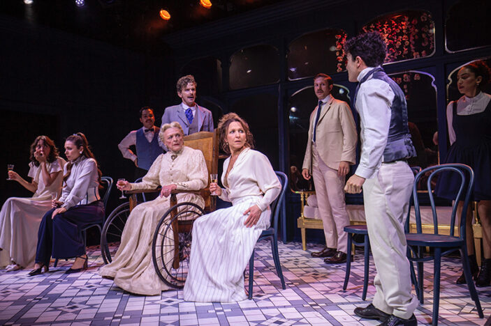 A group of performers in period costumes stand on a stage staring in shock at a young man.